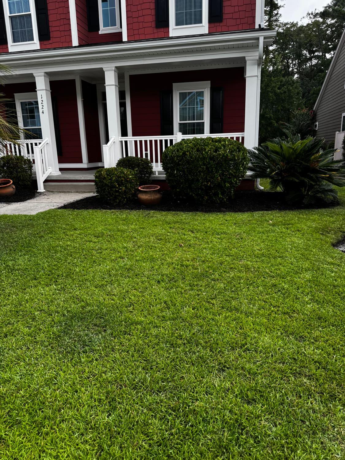 Freshly cut, edged front lawn in front of a red-sided Myrtle Beach home